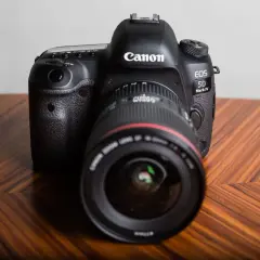 Profesjonalny aparat Canon EOS 5D Mark IV na drewnianym stole. Dowiedz się, jak sprawdzić przebieg migawki Canon.