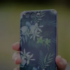 Dłoń trzyma telefon z motywem tropikalnych kwiatów. To jak przenośna galeria zdjęć w telefonie, pełna barw.