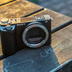 Czarny aparat Sony zve10 bez obiektywu leży na drewnianym blacie.