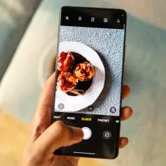 Rób apetyczne zdjęcia telefonem! Na ekranie smartfona deser na talerzu, a palec naciska spust migawki.