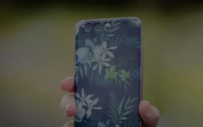 Dłoń trzyma telefon z motywem tropikalnych kwiatów. To jak przenośna galeria zdjęć w telefonie, pełna barw.
