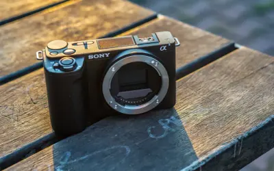 Czarny aparat Sony zve10 bez obiektywu leży na drewnianym blacie.