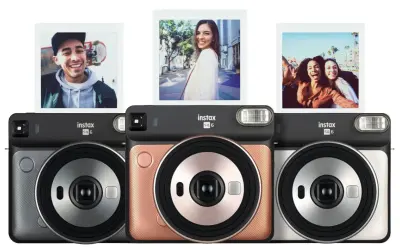 Aparat natychmiastowy Instax SQ6 w trzech kolorach: szarym, różowym i srebrnym. Nad aparatami widoczne są trzy zdjęcia zrobione tym modelem.