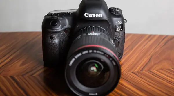 Profesjonalny aparat Canon EOS 5D Mark IV na drewnianym stole. Dowiedz się, jak sprawdzić przebieg migawki Canon.