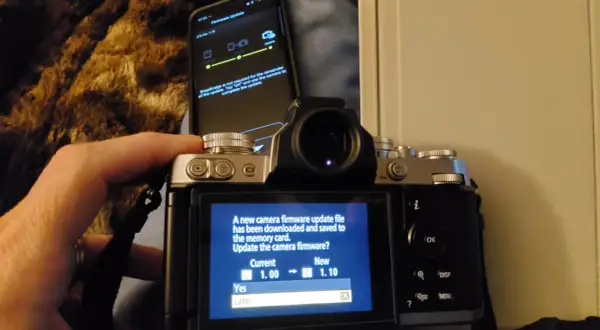 Aktualizacja oprogramowania aparatu Nikon z telefonu. Ekran aparatu pokazuje komunikat o pobraniu pliku aktualizacji i pytanie, czy chcesz zaktualizować oprogramowanie.