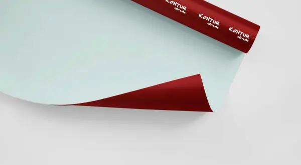 Rolka czerwonej folii samoprzylepnej z białym logo "KONTUR druk" na jasnoniebieskim tle.