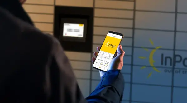Mężczyzna trzyma smartfon z aplikacją InPost, obok znajduje się Paczkomat. Czy do nadania paczki InPost potrzebna jest etykieta? Aplikacja pokazuje opcje wysyłki.