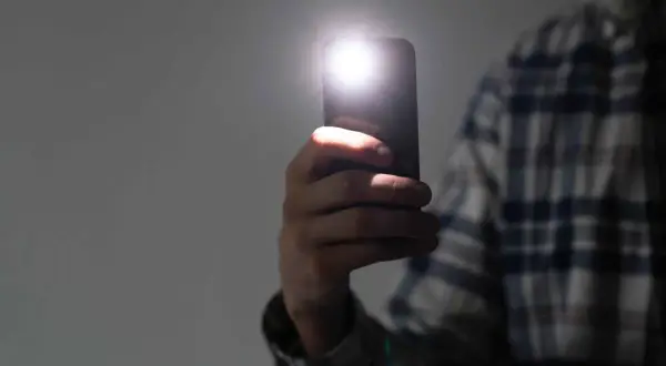 Dłoń trzyma smartfon Samsung, którego lampa błyskowa świeci. Zastanawiasz się, dlaczego nie działa lampa błyskowa w aparacie Samsung?