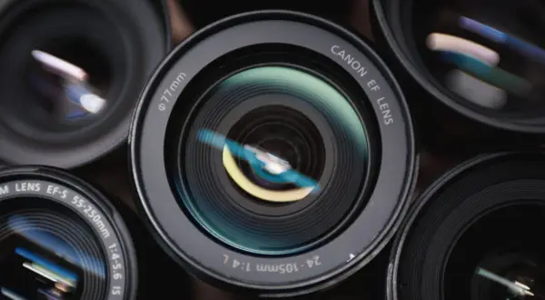 Zbliżenie na kilka obiektywów fotograficznych. Centralny obiektyw Canon EF 24-105mm 1:4 L pokazuje, co daje jasny obiektyw – piękne odbicia światła.