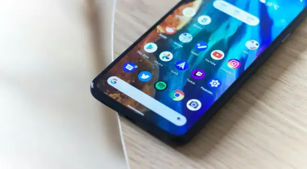 Smartfon z kolorową tapetą i ikonami aplikacji, w tym aparatu. Dowiedz się, jak dodać aparat do ekranu głównego.