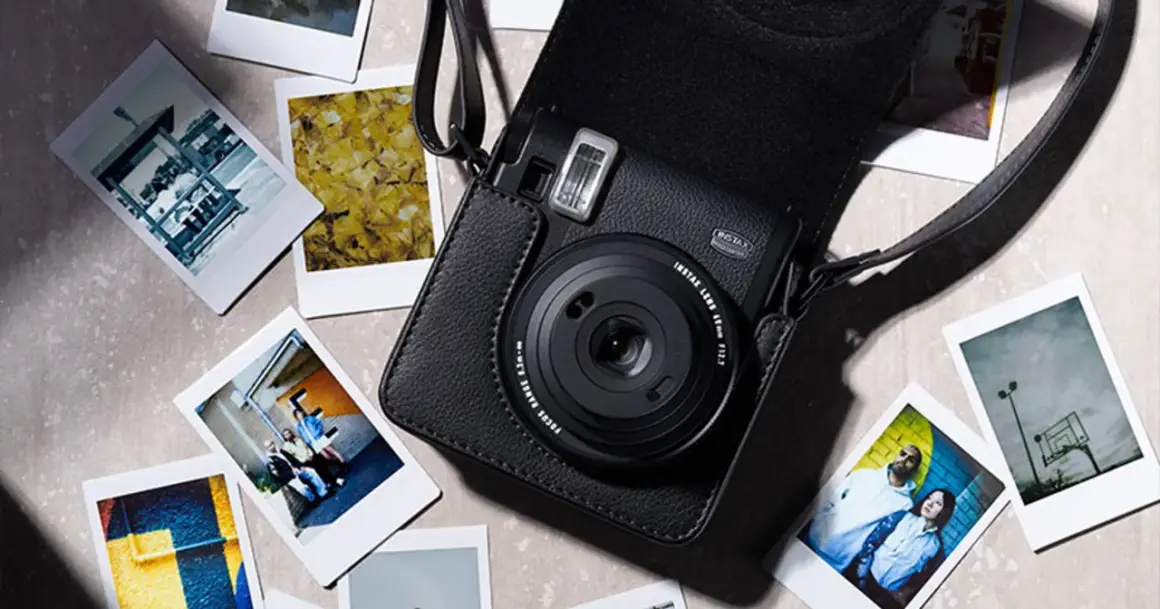 Czarny aparat Instax w skórzanym etui, otoczony kilkoma natychmiastowymi zdjęciami. To właśnie instax co to za magia tworzenia wspomnień.
