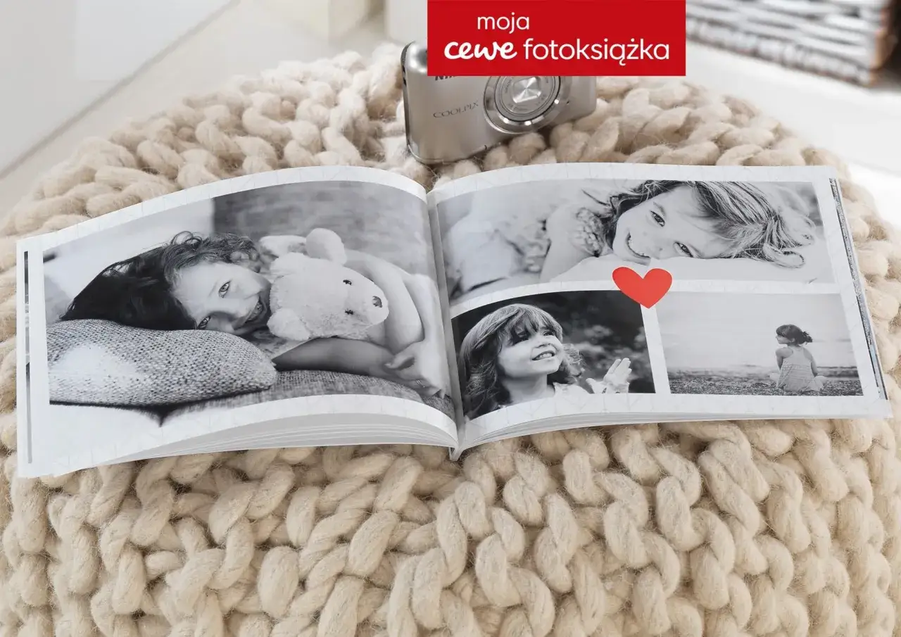 Otwarta fotoksiążka z czarno-białymi zdjęciami dzieci, obok aparat Coolpix. Sprawdź cewe fotoksiążka cennik.